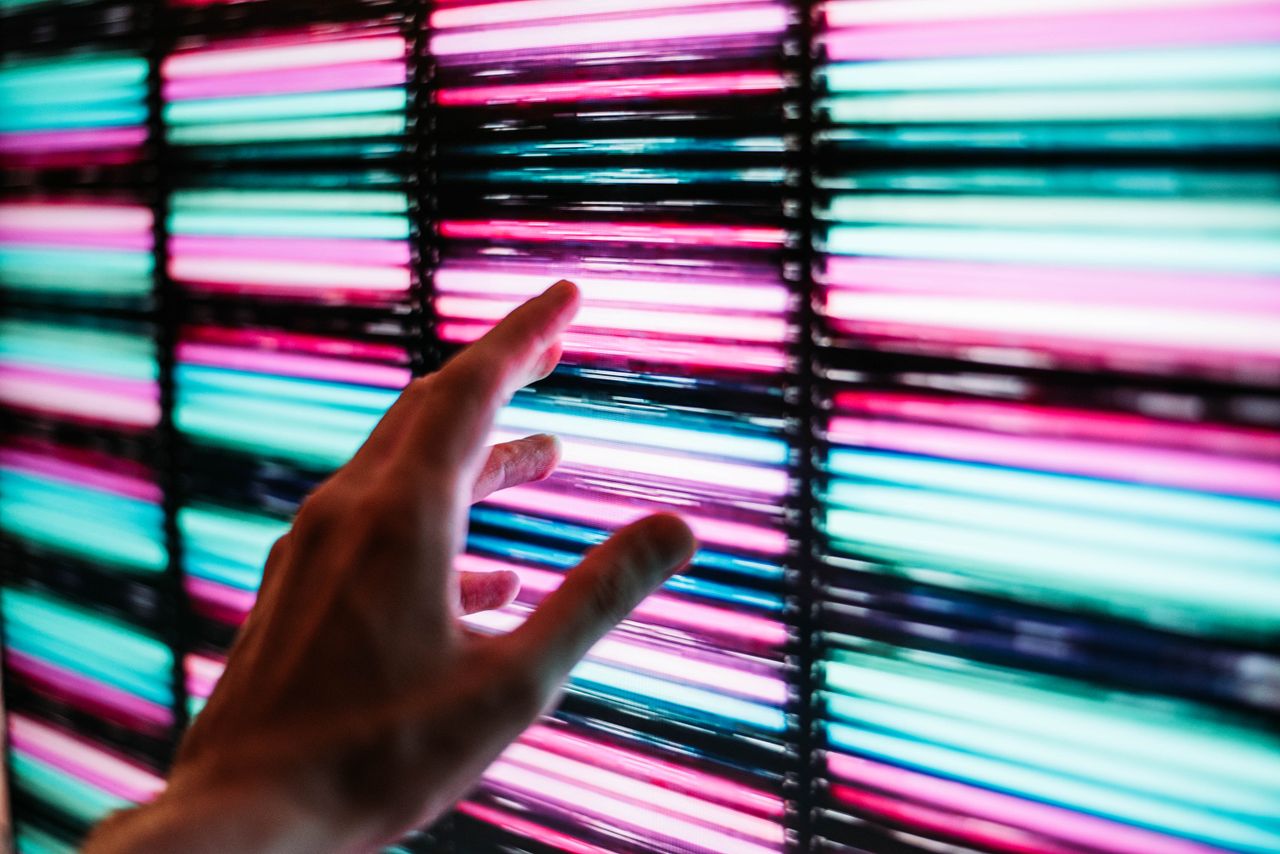 Vibrant LED lights in blue and pink, with a hand reaching out, showcasing modern technology and interaction.