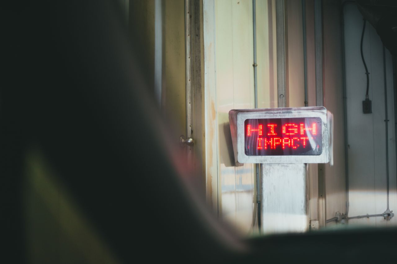 A red LED sign displaying 'HIGH IMPACT' in an indoor setting.